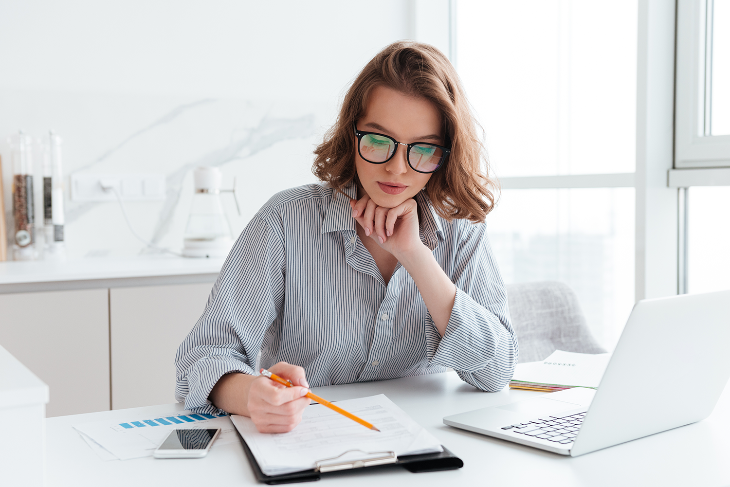 young-concentrated-businesswoman-glasses-striped-shirt-working-with-papers-home